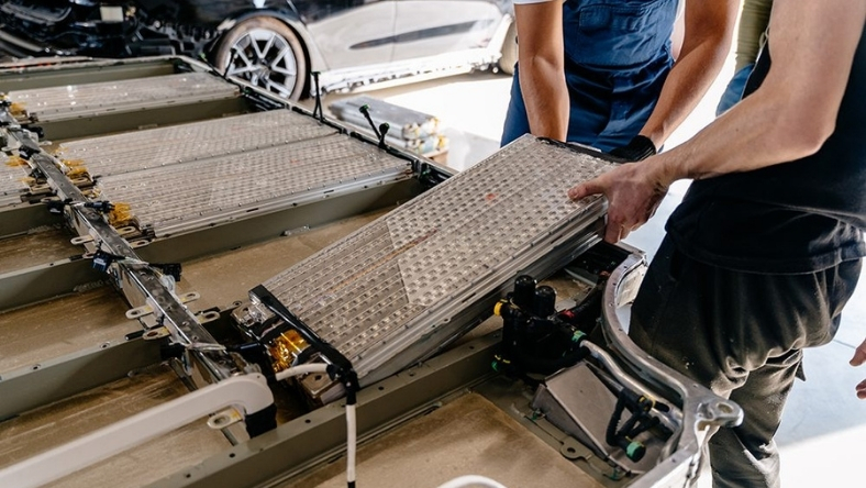 Technicians installing EV battery module in electric car
